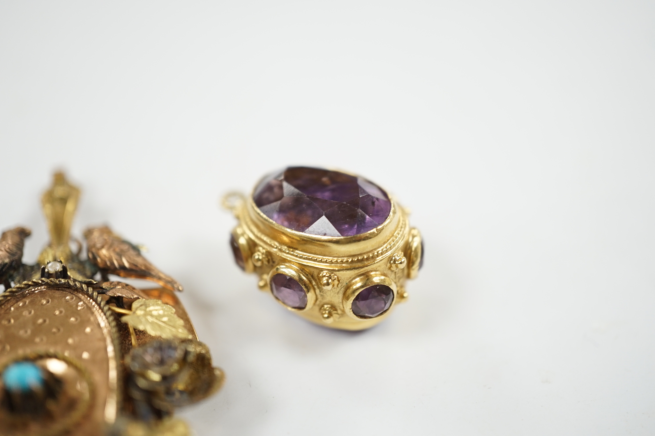 A Victorian three colour yellow metal, turquoise and seed pearl set pendant, decorated with birds and foliage, with glazed back, overall 65mm, together with a yellow metal and eight stone amethyst set charm.